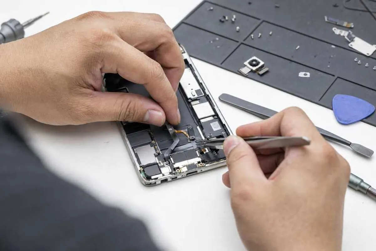 Técnico substituindo alto-falante e microfone de smartphone em bancada de reparo