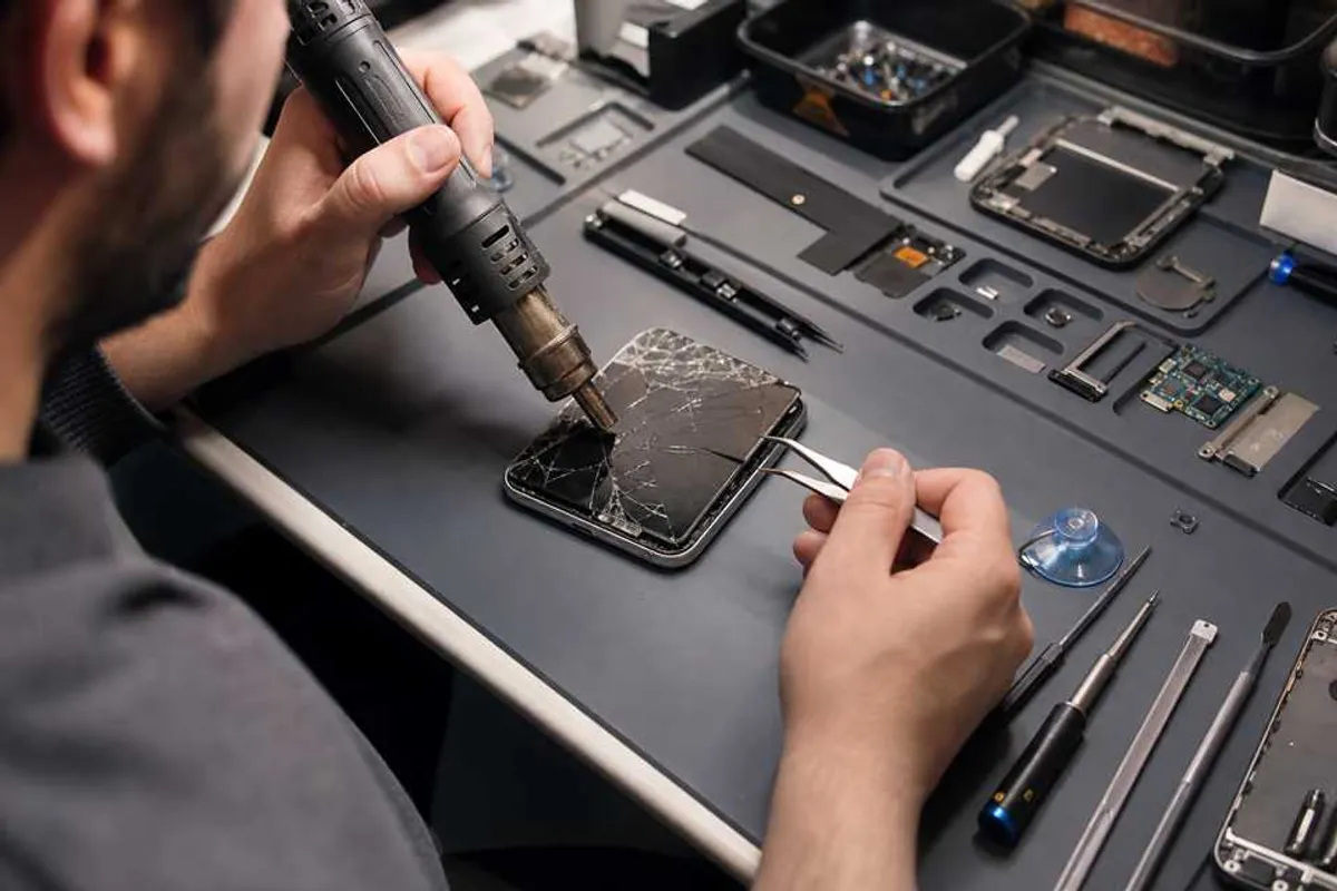 Técnico consertando smartphone em bancada profissional de assistência técnica