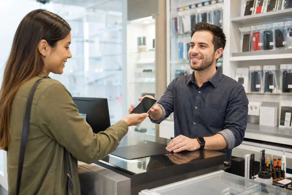 Assistência técnica de celular entregando aparelho reparado ao cliente em balcão de loja moderna